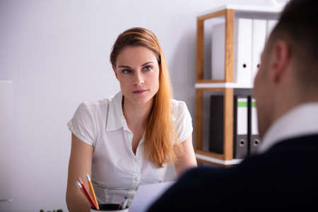 Blonde Young Female Recruiter Looking At Candidate In Office