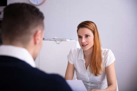 Blonde Young Female Recruiter Looking At Candidate In Officeの写真素材