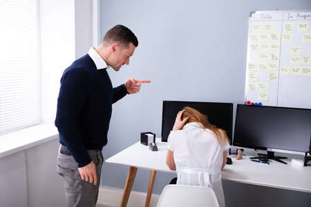 Angry Businessman Shouting At Female Executive In Officeの写真素材