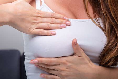 Close-up Of Woman's Hand Pressing Her Breastの写真素材