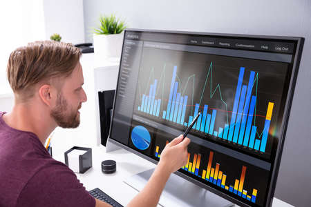 Close-up Of Businessman Analyzing Graph On Laptop At Workplace In The Office