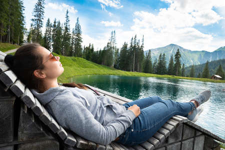 Woman Relaxing In Sun Lounger Near Lake In Mountainsの写真素材