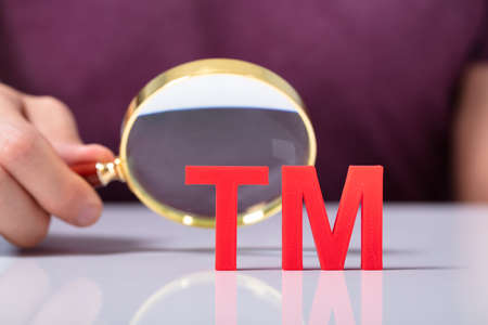 Close-up Of Human Hand's Holding Magnifying Glass Looking Red Trademark Tm Iconの写真素材