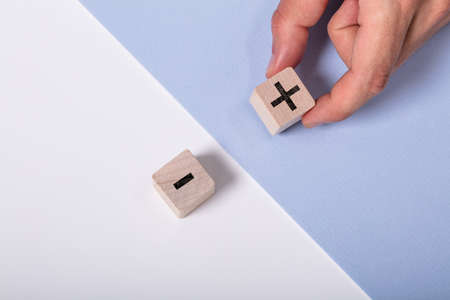 Person Holding Plus Sign Block Against Minus
