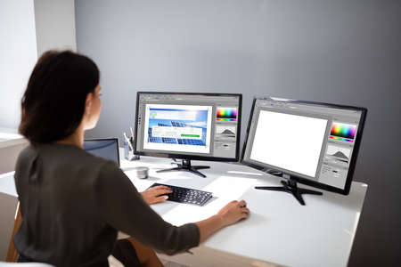 Close-up Of A Female Designer Working On Multiple Monitors At Workplace