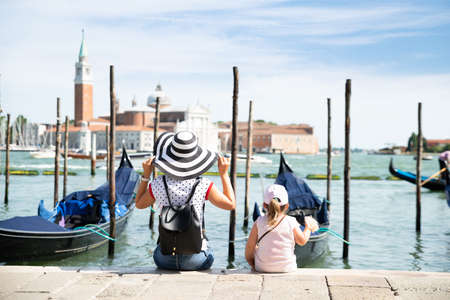 Mother And Daughter Sitting In Front Of Gondolas Looking At San Giorgio Maggioreの写真素材