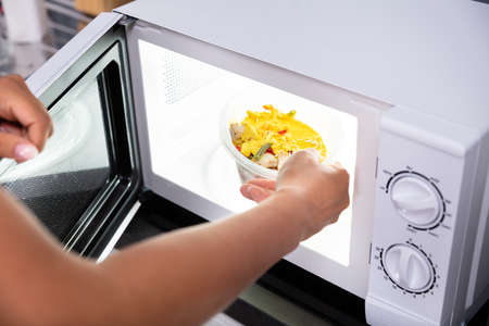 Close-up Of A Person Heating Food In Microwave Ovenの写真素材