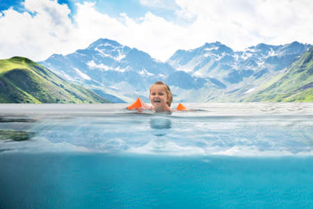 Little Girl Swimming In Infinity Pool In Mountainsの写真素材