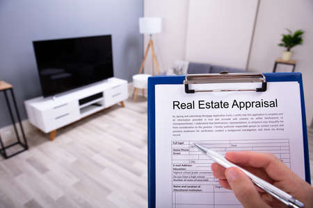 Close-up Of A Person's Hand Filling Real Estate Appraisal Form With Penの写真素材