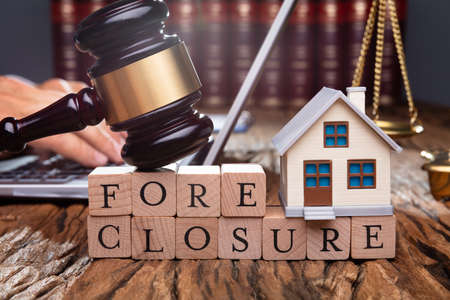 Cropped Image Of Judge Holding Gavel On House Model At Desk
