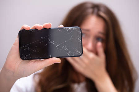 Woman Hand Holding Smartphone With Cracked Screenの写真素材