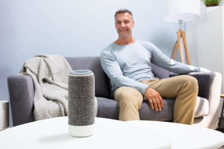 Close-up Of Wireless Speaker In Front Of Man Sitting On Sofaの写真素材