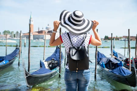 Rear View Of Young Woman Holding Her Stripes Hat While Looking At San Giorgio Maggioreの写真素材