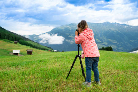 Little Girl Taking Photo Of Scenic Mountain Landscapeの写真素材