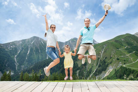 Happy Family With Little Girl Jumping In Austrian Mountains In Summerの写真素材