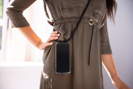 Mid-section Of Woman Carrying Mobile Phone In Officeの写真素材