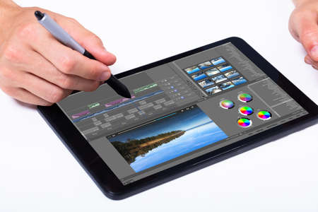 Young male editor editing video on tablet at workplace