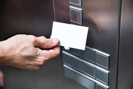 Close-up Of A Person Holding Key Card Near Elevator Buttonの写真素材