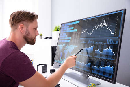 Close-up Of Businessman Analyzing Graph On Laptop At Workplace In The Office
