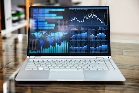 Close-up Of Laptop Computer Showing Graph On Office Deskの写真素材