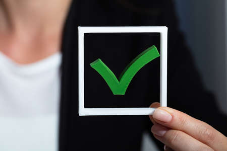 Close-up Of A Businessperson's Hand Holding Green Check Mark Iconの写真素材