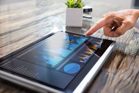 Close-up Of A Businessman's Hand Analyzing Graph On Convertible Laptopの写真素材