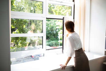 Side View Of A Businesswoman Looking Out Of A Window From An Office Buildingの写真素材