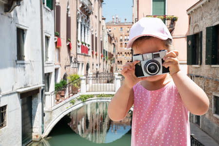 Little Girl Taking A Picture On Camera With Houses And Canal At Background In Veniceの写真素材