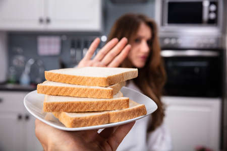 Young Woman Refusing Bread Slice On Plate At Home
