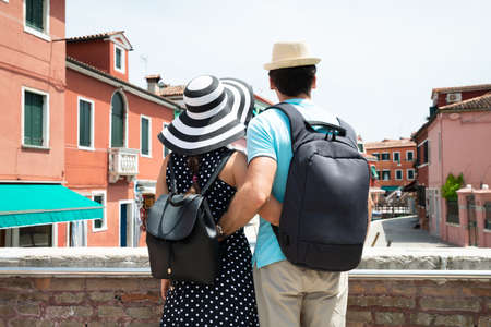 Rear View Of A Couple Tourist With Their Backpack Standing Together Looking At Venice Streetの写真素材