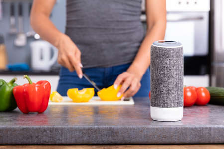 Close-up Of A Woman Working In Kitchen With Smart Speaker In Foregroundの写真素材