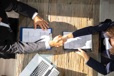 An Elevated View Of A Male Manager Shaking Hands With Female Applicant At Workplace