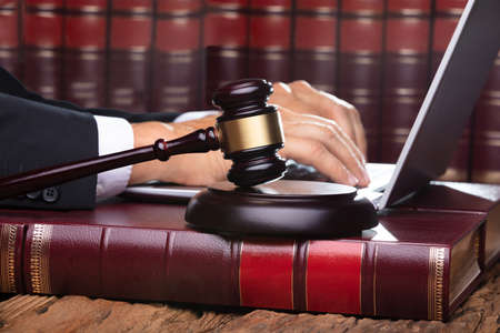 Male Judge In A Courtroom Typing On Laptop On Front Of Gavel