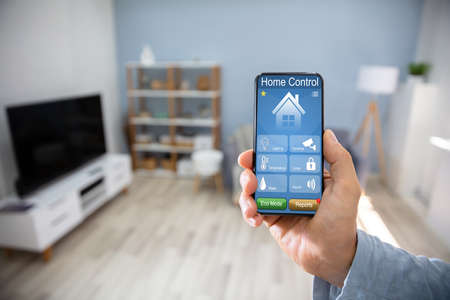 Man Using Smart Home Application On Mobile Phone