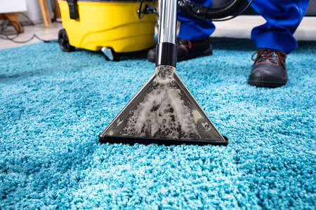 Close-up Of A Person Cleaning Carpet With Vacuum Cleanerの写真素材