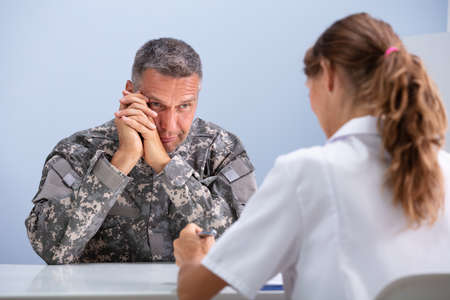 Close-up Of Depressed Army Soldier Suffering From Ptsd During Psychotherapy Session At Doctor's...