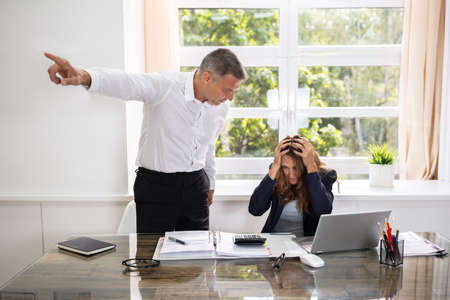 Angry Mature Businessman Firing Upset Female Employee In Office