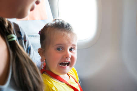 Little Girl Sitting Next To Mother Crying On Airplaneの写真素材