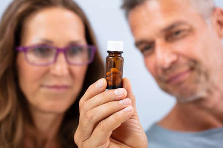 Mature Couple Looking At Closed Bottle Filled With Pillsの写真素材