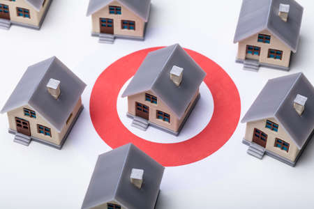 House Models On Darts Target Surrounded With Other Architectural Buildings Over White Backgroundの写真素材