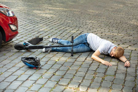 Man After Accident On Electric Scooter Overrun By Carの写真素材