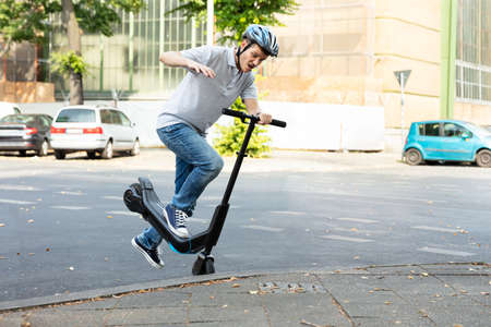 Man Having Accident Falling From E-Scooter On Streetの写真素材
