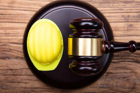 High Angle View Of Yellow Hard Hat And Gavel Arranged On Wooden Desk