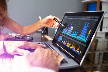 Close- Up Of Office Workers Analyzing Graph On Laptop With His Coworker