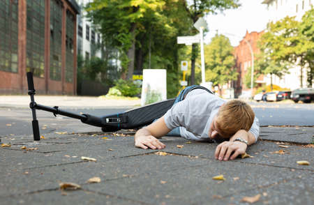 Unconscious Man Lying On Concrete Street After Accident With An Electric Scooterの写真素材