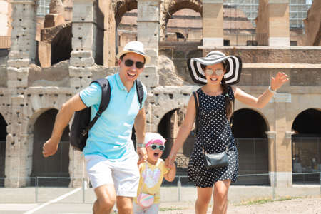 Young Tourist Family Running In Front Of Colosseum In Rome, Italyの写真素材