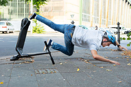 Man Having Accident Falling From E-Scooter On Streetの写真素材