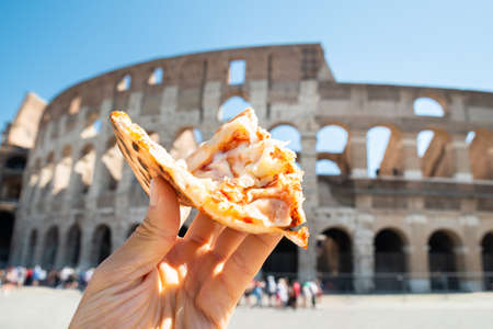 Hand Holding Slice Of Italian Pizza Near Colosseum, Romeの写真素材