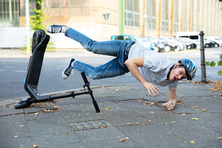 Man Having Accident Falling From E-Scooter On Streetの写真素材