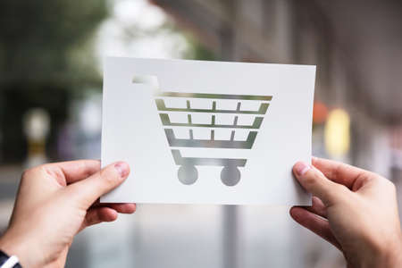 Hands Holding Paper With Cutout Shopping Cart Outdoorsの写真素材